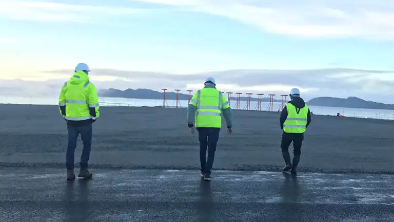 Tre personer i gule veste går på den 1. etape af landingsbanen i Nuuk